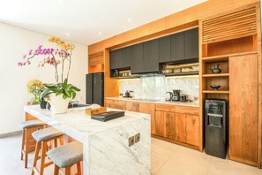 A modern kitchen with a marble island, wooden cabinets, and a built-in water dispenser. - Brand new Luxury 5 br Villa 200m to Brawah Beach (Canggu)