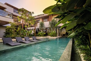 A modern hotel with a swimming pool, lounge chairs, and lush greenery. - Brand new Luxury 5 br Villa 200m to Brawah Beach (Canggu)