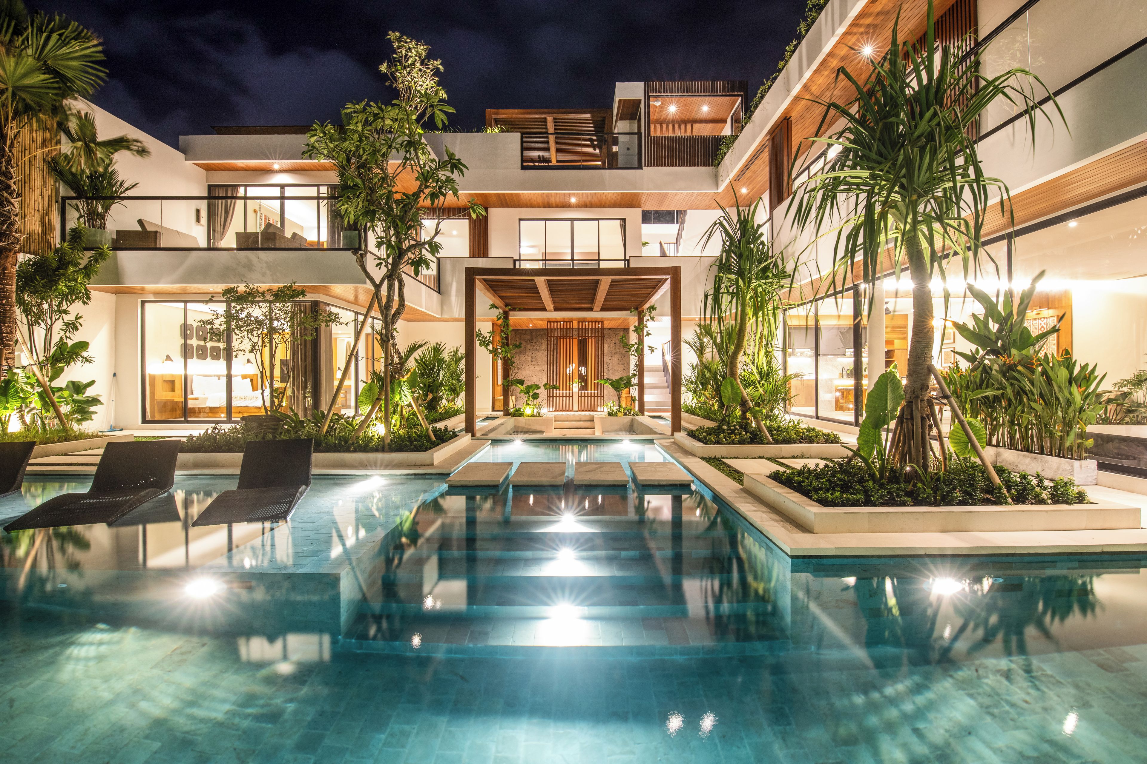A modern pool area with lounge chairs, a clear pool, and surrounding greenery.