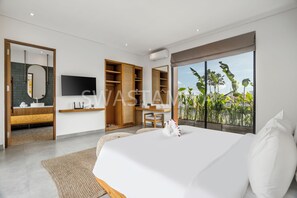 A modern bedroom with a large bed, a TV, a wardrobe, and a view of greenery. - Brand new Luxury 5 br Villa 200m to Brawah Beach (Canggu)