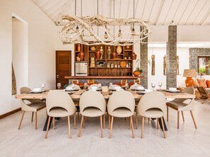 A dining area with a wooden table, beige chairs, and a decorative ceiling piece. - Luxurious 5BR Dream Villa, 200m to Berawa Beach (Canggu)