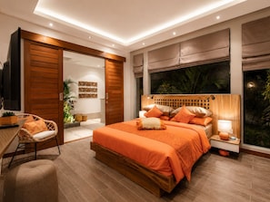 Un dormitorio moderno con una cama grande, un cabecero de madera, una mesita de noche, una silla y vistas al exterior.