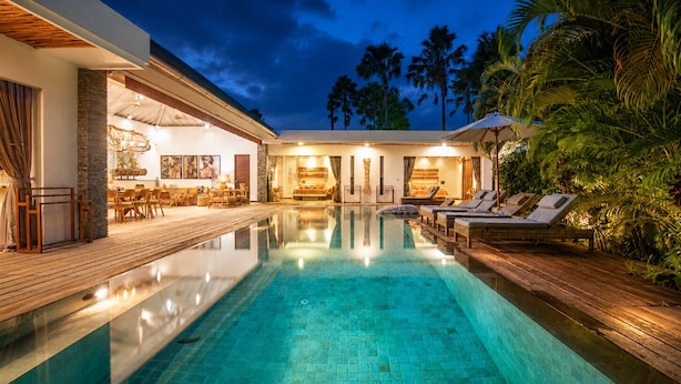 A modern pool area with a clear pool, wooden deck, and lounge chairs. - Luxurious 5BR Dream Villa, 200m to Berawa Beach (Canggu)