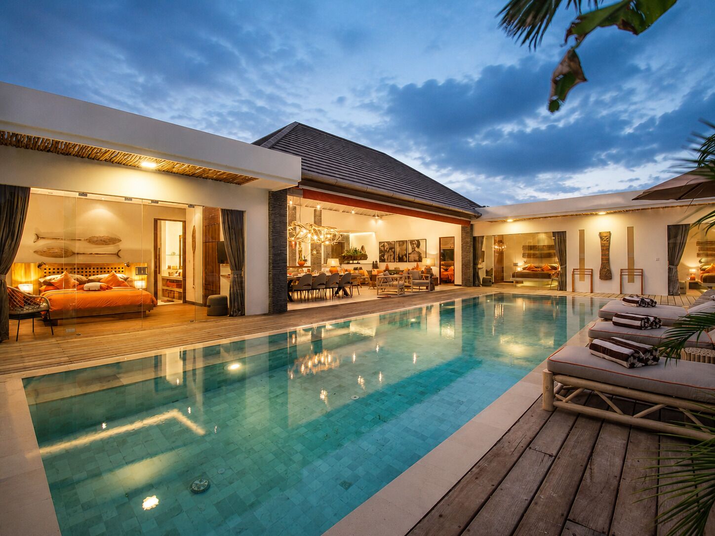 A modern resort with a swimming pool, a dining area, and a bedroom with a view of the pool.