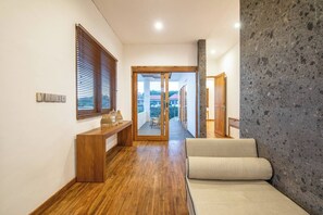 Un couloir avec un plancher en bois, un banc et un canapé.