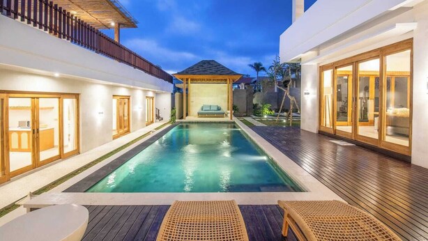 A modern pool area with a wooden deck, a lounge chair, and a covered seating area. - Luxurious 6 BR With Sea View, 5 Mins to Savaya (Pecatu)