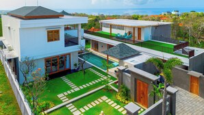 A modern two-story house with a swimming pool, a balcony, and a view of the ocean. - Luxurious 6 BR With Sea View, 5 Mins to Savaya (Pecatu)