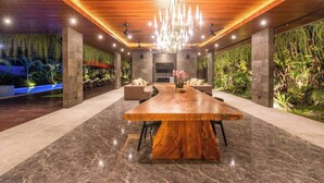 A modern dining area with a large wooden table, marble flooring, and a chandelier. - Stylish 5BR Private Villa, Central Seminyak (Seminyak)