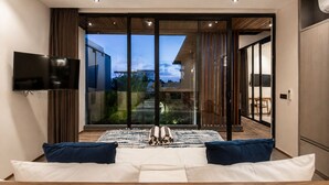A modern bedroom with a large bed, a flat-screen TV, and a sliding glass door leading to a balcony. - Stylish 5BR Beach Villa, 200m in Boho Canggu (Munggu)