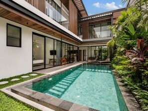 A modern house with a swimming pool, large glass windows, and a garden. - Elegant 5BR Villa Retreat Steps From Canggu Beach (Munggu)
