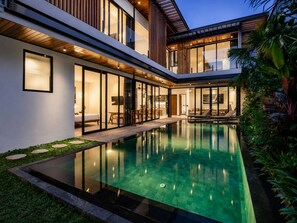 A modern house with a swimming pool, large windows, and a well-maintained garden. - Stylish 5BR Beach Villa, 200m in Boho Canggu (Munggu)