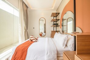 A modern hotel room with a large bed, a wooden dresser, and two mirrors.
