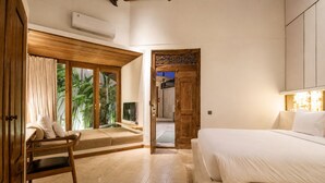 Un dormitorio con cama, una silla, una ventana con cortinas y una puerta que da a otra habitación.