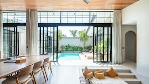A modern interior with a dining area, a pool, and a seating area with steps leading to a balcony. - Bohemian Lush 5BR Retreat, 5 Mins to Bingin Beach (Pecatu)