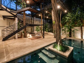 Un espace piscine intérieur moderne, doté d’un escalier, de sièges et d’arbres.