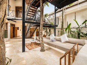 Un amplio espacio interior con una escalera, un sofá con cojines y una mesa de centro.