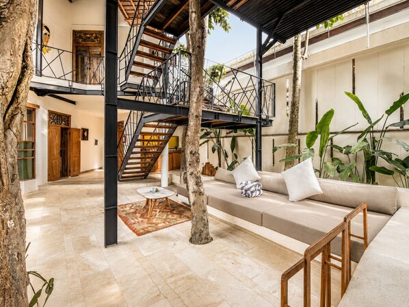 Un amplio espacio interior con una escalera, un sofá con cojines y una mesa de centro.