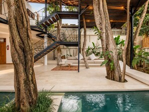 Un intérieur moderne avec un escalier, une piscine et des plantes d’intérieur.