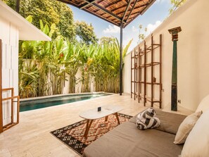 Uma área de piscina com um sofá, uma mesa pequena e um tapete estampado.