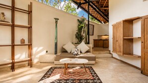 A modern interior with a sofa, coffee table, and wooden shelves. - Serene 1BR Villa 800 to Echo Beach, With Pool (Canggu)