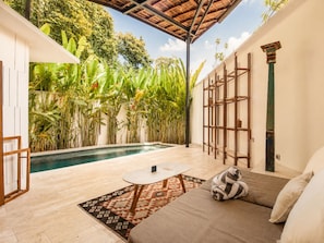A pool area with a sofa, a small table, and a patterned rug. - Serene 1BR Villa 800 to Echo Beach, With Pool (Canggu)