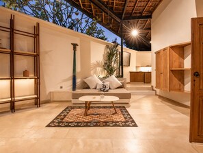 A modern interior with a sofa, a coffee table, a patterned rug, wooden shelving, and a door. - Serene 1BR Villa 800 to Echo Beach, With Pool (Canggu)