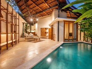A modern indoor pool area with a wooden ceiling, a sofa, and a dining table. - Serene 1BR Villa 800 to Echo Beach, With Pool (Canggu)