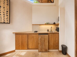A compact kitchen with wooden cabinets, a sink, and a small countertop. - Serene 1BR Villa 800 to Echo Beach, With Pool (Canggu)