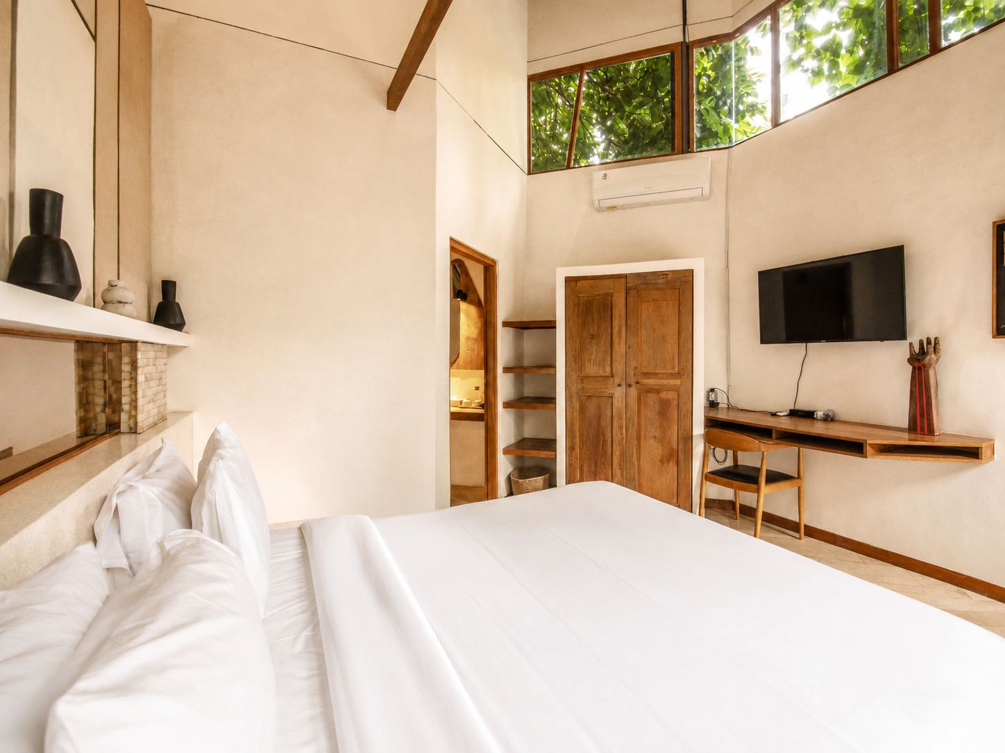 Une chambre à coucher avec un lit, un bureau, une télévision et une armoire.