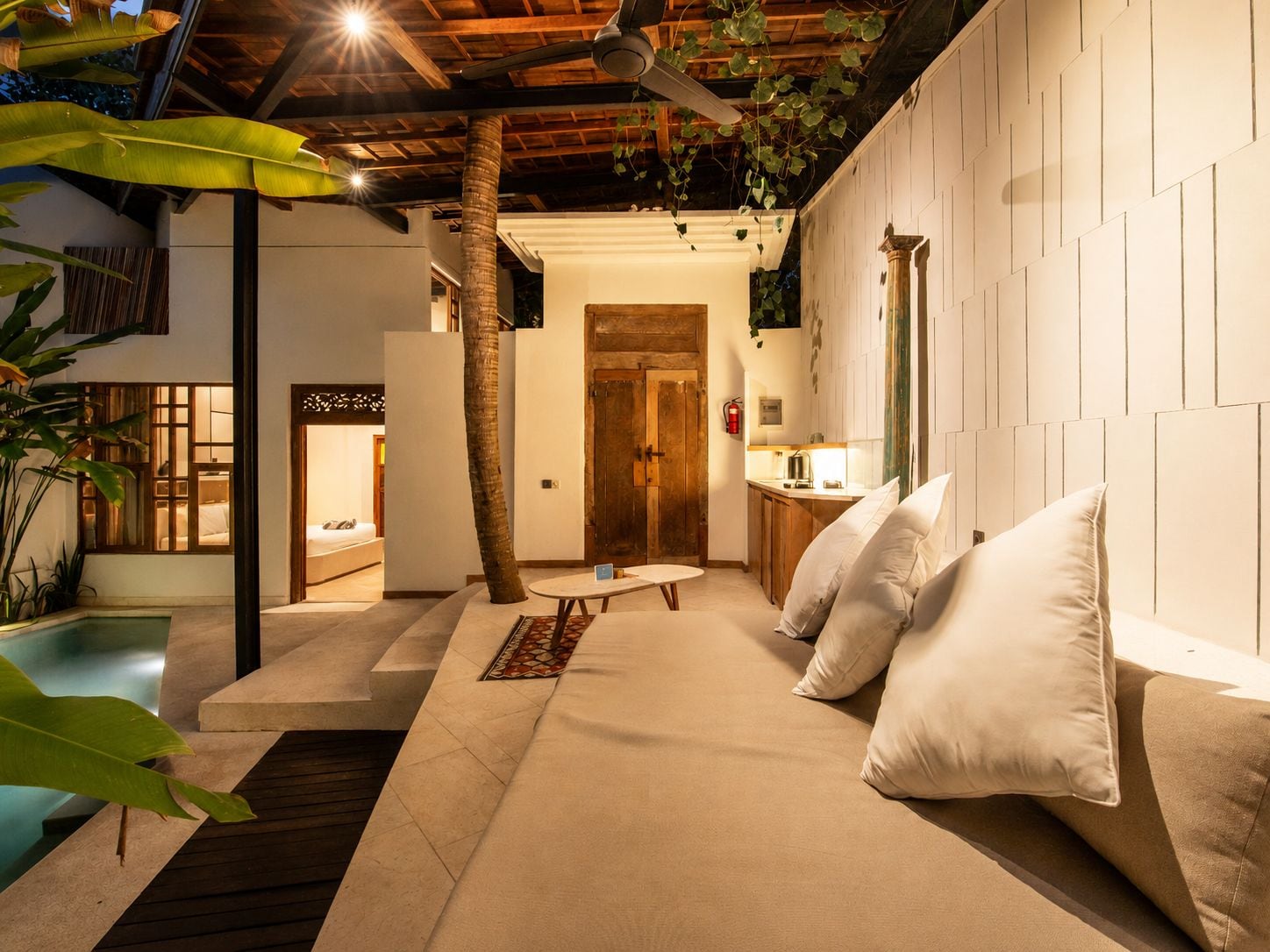 A modern interior with a pool, a wooden door, and a seating area with cushions.