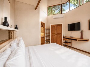 A bedroom with a bed, a TV, a desk, and a wardrobe.