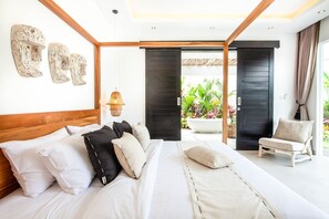 Une chambre moderne avec un grand lit, une tête de lit en bois et une vue sur un jardin, visible à travers une porte ouverte.