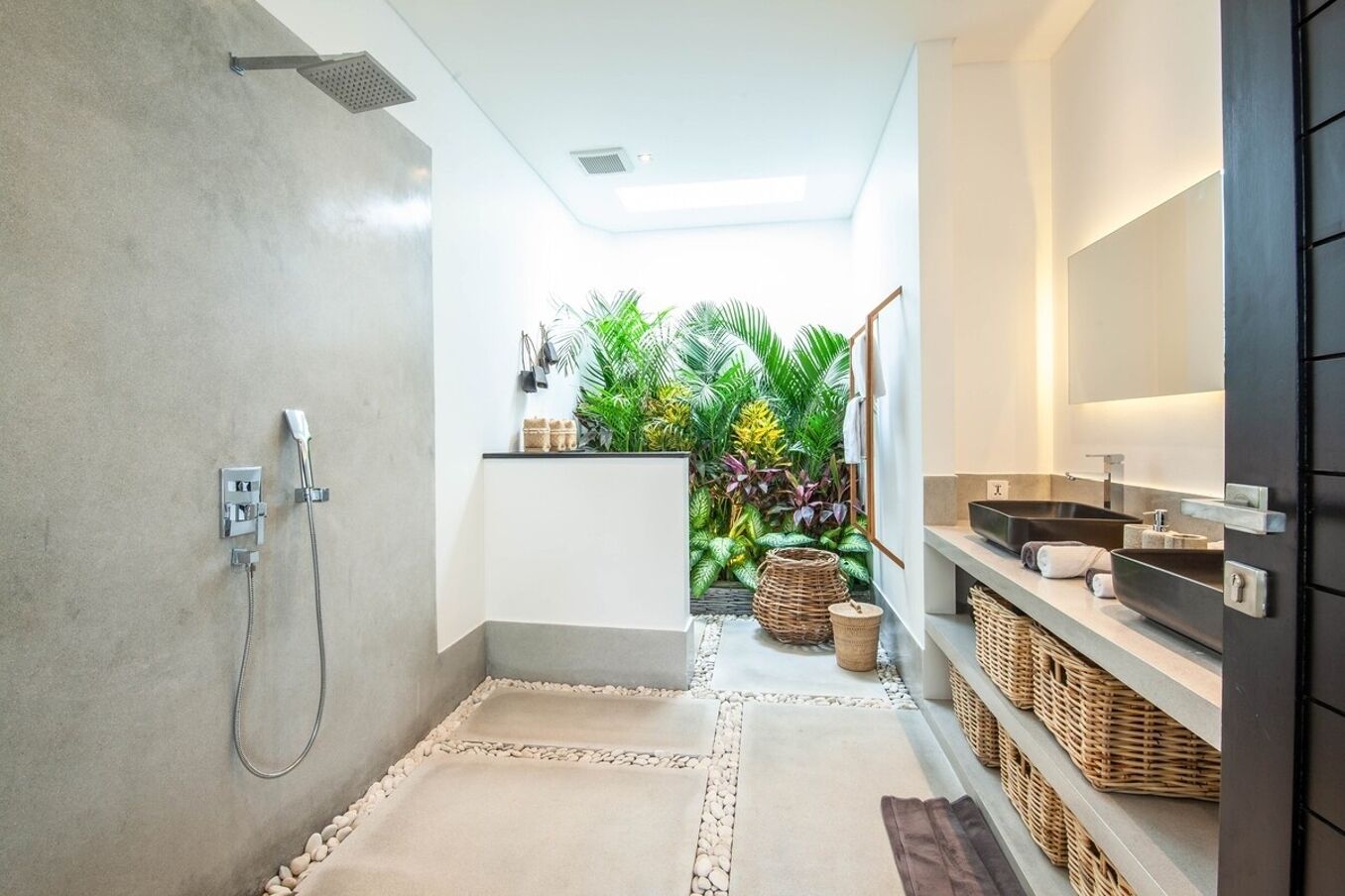 Un bagno moderno con doccia, due lavandini, uno specchio grande e un piccolo angolo dedicato alle piante.