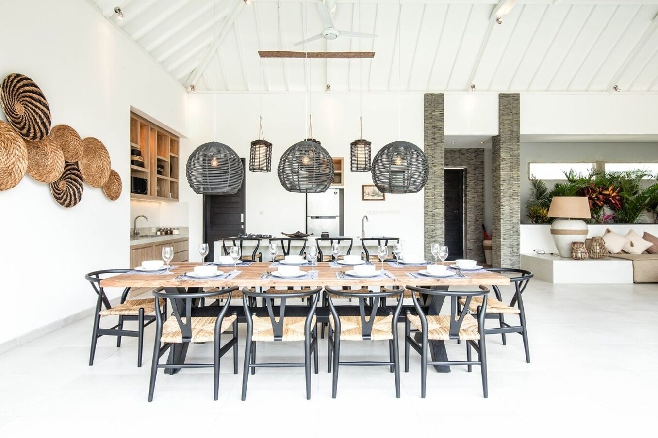 A spacious dining area with a long wooden table set for six, surrounded by black chairs.