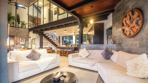 A spacious living area with two white sofas, a coffee table, and a staircase leading to an upper level. - Elegant 6BR Clifftop Villa Near Bingin (Pecatu)