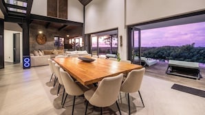 A spacious living area with a large wooden dining table, comfortable seating, and a view of the outdoors. - Elegant 6BR Clifftop Villa Near Bingin (Pecatu)