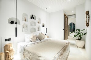 Un dormitorio moderno con una cama grande, una mesita de noche de madera, una planta en maceta y estantes fijos en la pared con objetos decorativos.