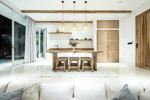 Una cocina moderna con una isla de madera, luces colgantes y un amplio ventanal corredera.