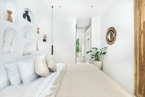 A hallway with a bed, a plant, and wall-mounted decor.