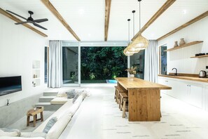 Een moderne keuken met een houten eiland, witte kasten en een groot raam met uitzicht op groen.
