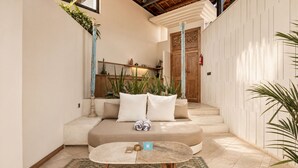 A cozy seating area with a sofa, pillows, and a small round table. - Sumptuous 1-br Villa Near Canggu Beach, 800m Away (Canggu)