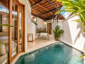 An indoor swimming pool with a wooden ceiling, a sofa, and potted plants. - Opulent 1-br Villa Just 800m From Canggu Beach (Canggu)