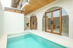 Un'area piscina moderna con piscina limpida, porte in legno e parete in vetro.