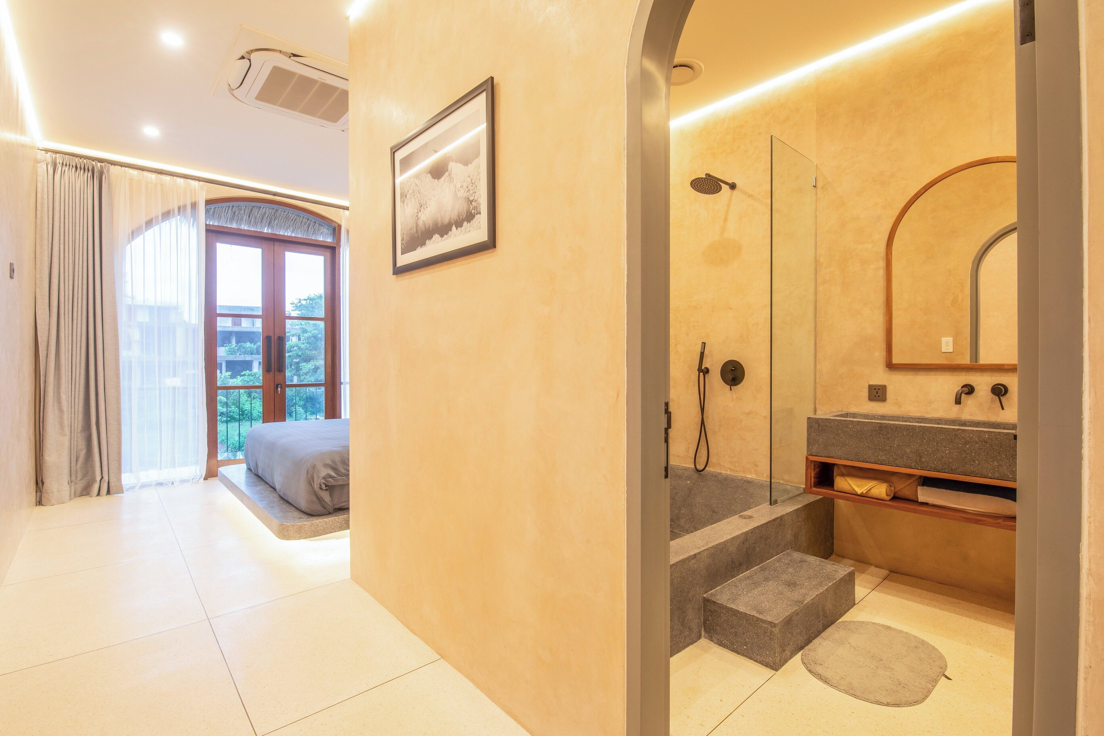 Une salle de bain moderne avec une douche, un lavabo et un grand miroir. Un escalier mène à un balcon.
