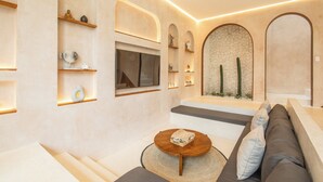 Un intérieur moderne avec un canapé, une table basse et des étagères ornées d’objets décoratifs.