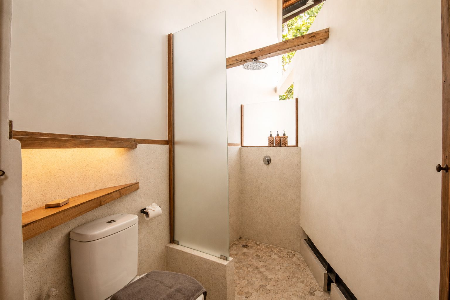 Ein kleines Badezimmer mit Toilette, Dusche und Ablagefläche.