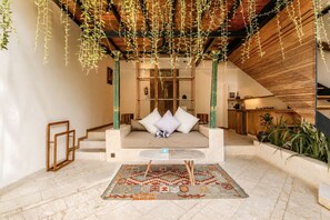 Egy modern belső tér, amelyben egy ülősarok, egy lépcsőház és a háttérben egy konyha található.