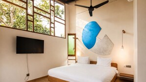 A bedroom with a bed, a TV, a ceiling fan, and a window with a view of trees. - Stylish 1-br Villa With Pool, 800m to Echo Beach (Canggu)