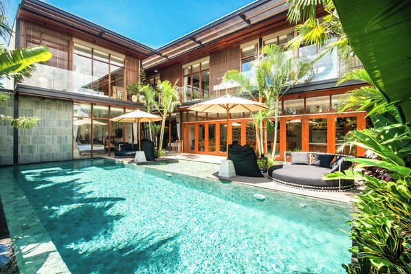 Ein moderner Poolbereich mit klarem Wasser, Liegestühlen und Sonnenschirmen.