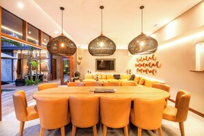 A modern dining area with a round table and orange chairs, large woven pendant lights, and a view of a pool outside. - Luxury 6BR Canggu 400m to Finns Beach (Canggu)